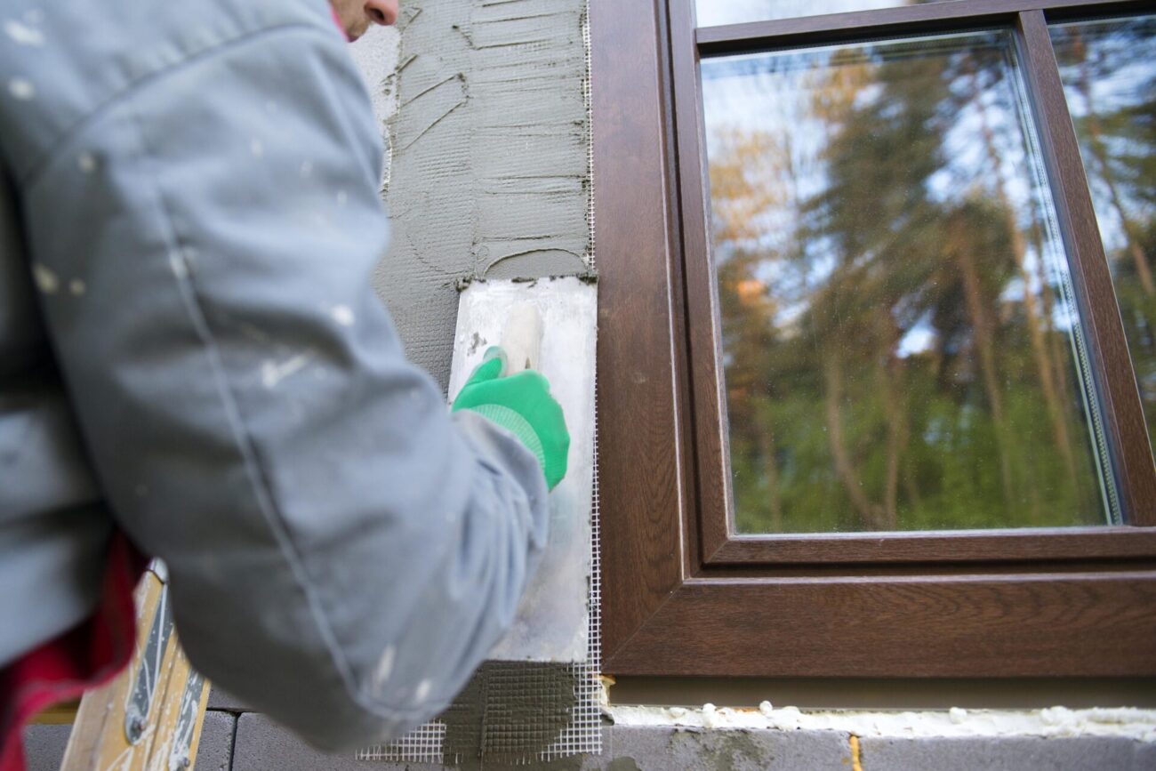 spreading out plaster with trowel around the windows after window replacement