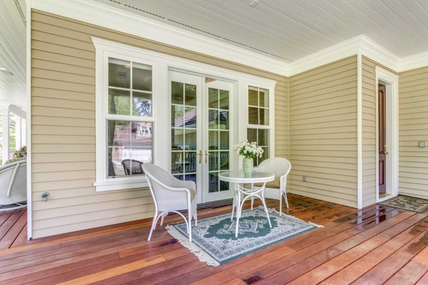 double hung windows on a covered deck with a table and chairs in front